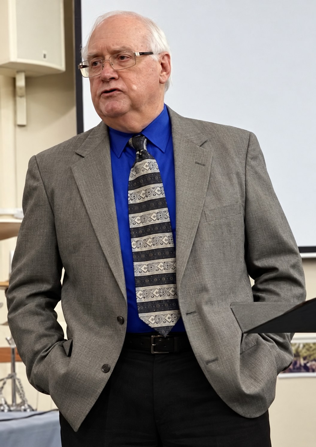 Ray Brewster speaking at a presentation, wearing a grey blazer and blue shirt